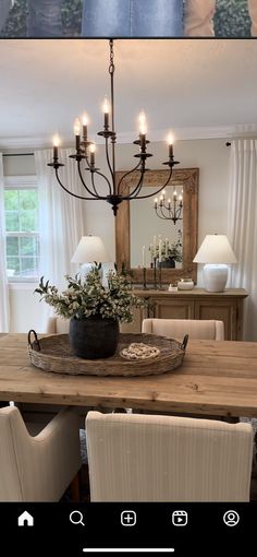 a dining room table with chairs and a tray on it's centerpiece in front of a mirror