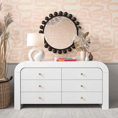 a white dresser topped with a mirror next to a lamp