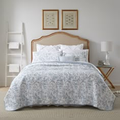 a bed with blue and white bedspread in a bedroom next to two pictures on the wall