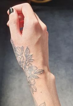 a woman's arm with a flower tattoo on the left side of her hand