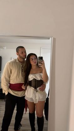 a man standing next to a woman taking a selfie in front of a mirror