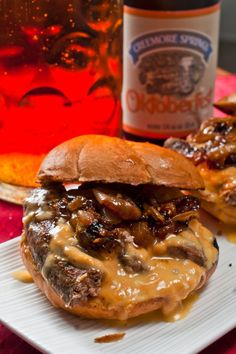 two hamburgers on a plate next to a bottle of beer