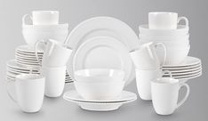 white dishes and cups are stacked on top of each other in front of a gray background