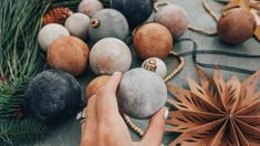 a woman is decorating christmas ornaments on the table with pine cones and other decorations