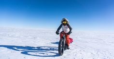 a person riding a bike in the snow on a sunny day with no one around