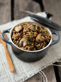 a bowl filled with food sitting on top of a table next to a wooden spoon