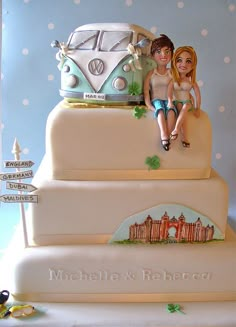 a wedding cake with two people sitting on the top tier and a vw bus in the background