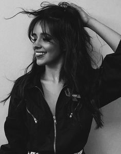 a black and white photo of a woman with her hair blowing in the wind, smiling