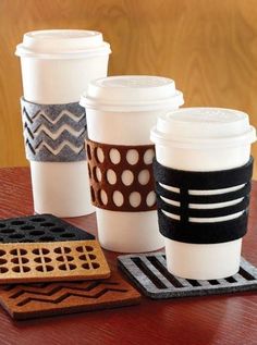 four coffee cups sitting next to each other on top of a wooden table with coasters