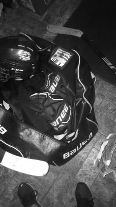 a black and white photo of a hockey bag on the ground next to some shoes