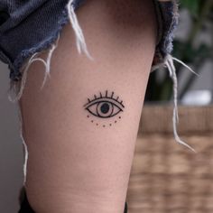 a woman's leg with an evil eye tattoo on the left side of her thigh