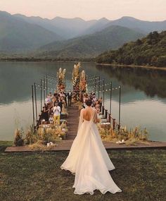 a woman standing on top of a grass covered field next to a lake