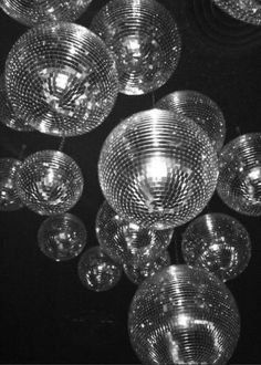 many glass bowls hanging from the ceiling in a restaurant or bar, black and white photo