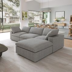 a large gray couch sitting in a living room next to a dining room and kitchen