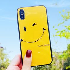 a person holding up a yellow phone case with a smiley face on it