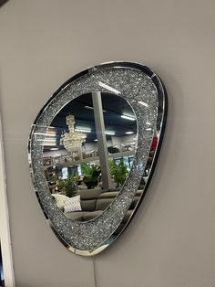 a mirror hanging on the side of a wall in front of a couch and chandelier