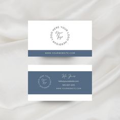 a white and blue business card sitting on top of a bed covered in sheets,