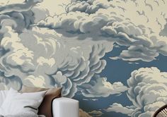 a bedroom with clouds painted on the wall next to a chair and lamp in front of it