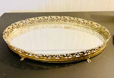 an ornately decorated gold tray sits on a black countertop next to a vase