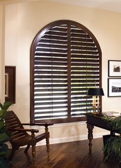 a living room filled with furniture and windows covered in wooden shutters, along with potted plants