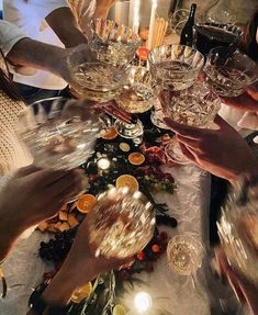 many people are holding wine glasses and toasting at a dinner table with candles on it