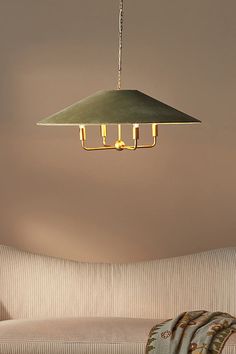 a green lamp hanging from the ceiling in a living room next to a beige couch