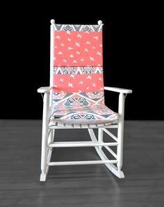 a white rocking chair with red and blue fabric