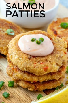 three crab cakes on a cutting board with a lemon wedge and sauce in the background