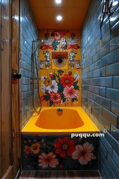 an orange sink in a tiled bathroom with flowers painted on the wall and below it