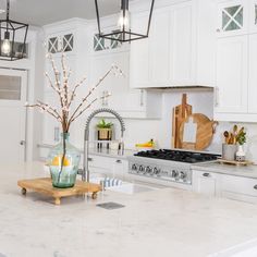 a kitchen with white cabinets and marble counter tops, along with an island in the middle