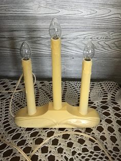 three yellow candles sitting on top of a doily