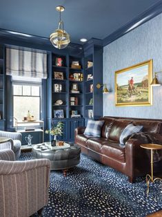 a living room with blue walls and leather furniture in the center, along with bookshelves