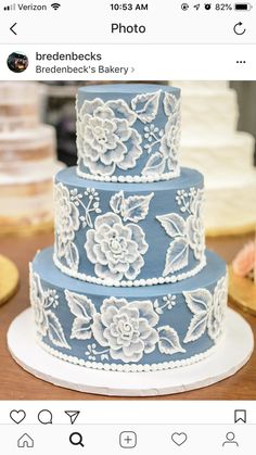 a three tiered blue and white wedding cake with flowers on the top, sitting on a table