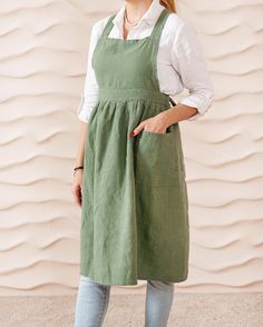 a woman standing in front of a wall wearing an apron