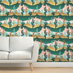 a couch sitting in front of a wallpaper with cactus and mountains on the side