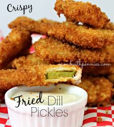 fried dill pickles with ranch dip in a small white bowl on a red and white checkered tablecloth