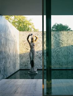 a statue is in the middle of a room with glass walls and doors on both sides