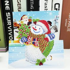 a christmas card with a snowman and santa clause on it next to some books