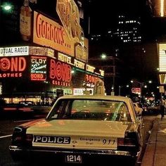 a police car is parked on the side of the road in front of neon signs