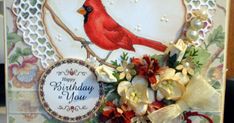 a happy birthday card with a red bird on a branch and flowers in the center