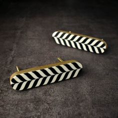 pair of black and white striped earrings with gold trimmings on the ends, sitting on a gray surface