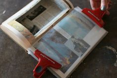 a person is holding a red stapler over an open book