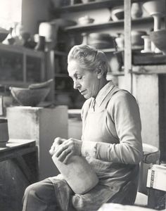 an old black and white photo of a woman working in a pottery shop