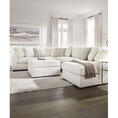 a living room with white furniture and wood floors