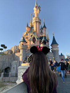 the back of a woman's head in front of a castle with people walking by