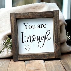 a sign that says you are enough on the side of a wooden table next to a pillow