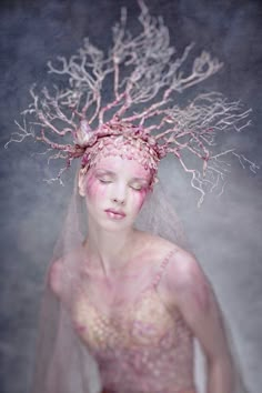 a woman wearing a veil and dress with branches on her head