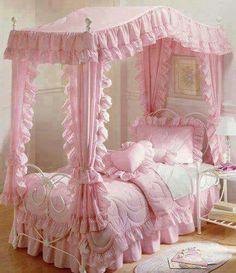 a pink canopy bed sitting on top of a wooden floor