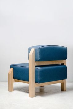 a blue chair sitting on top of a white floor next to a wooden frame wall