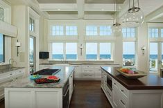 a large kitchen with white cabinets and an island in front of the window overlooking the ocean